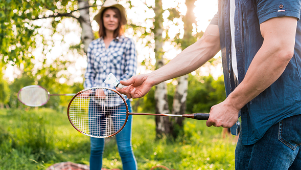 Happy couple playing badminton with shuttlecock and racket outdoors